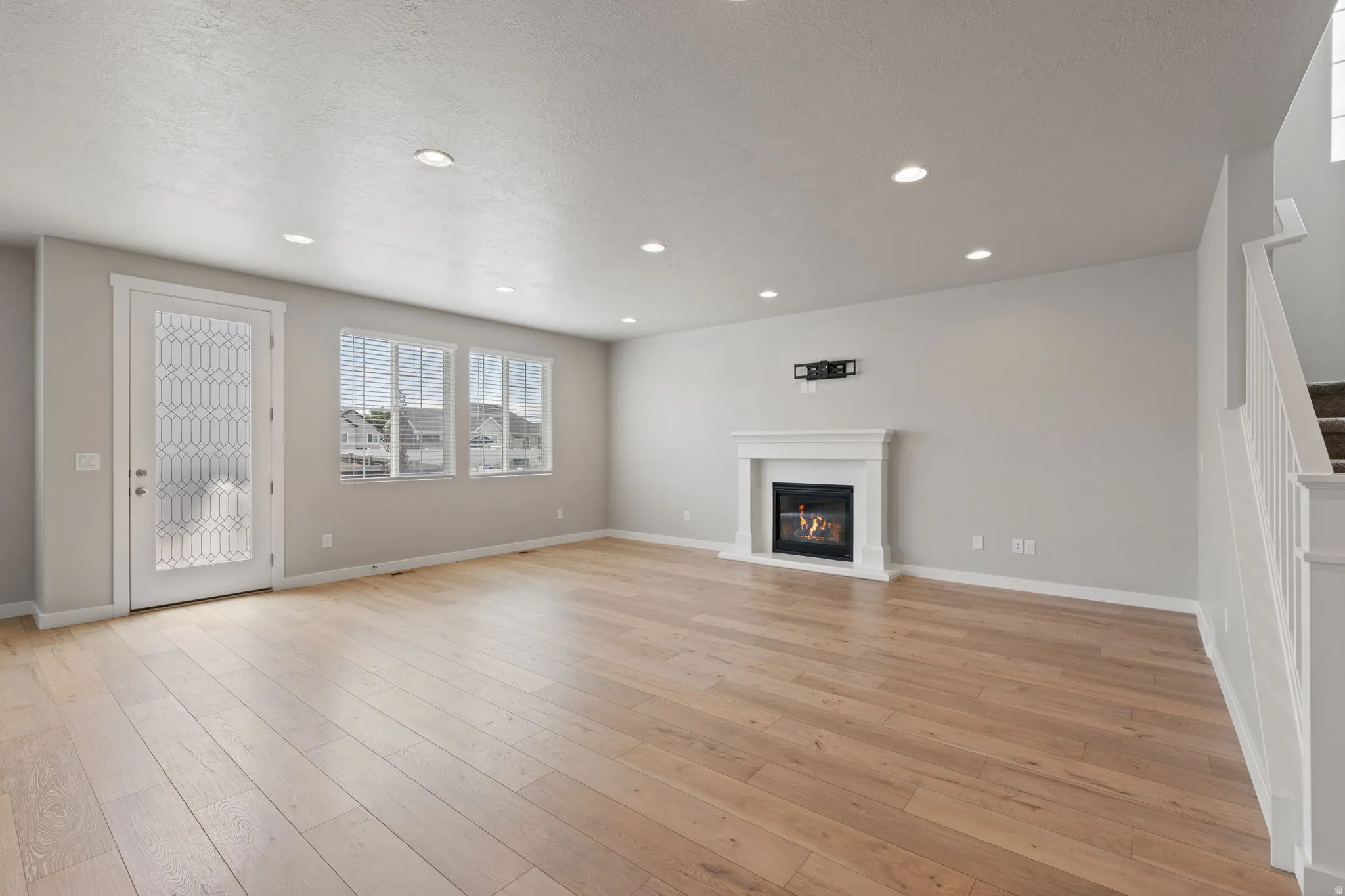 Spacious interior featuring wood-finish flooring, recessed lighting, and a white mantel fireplace