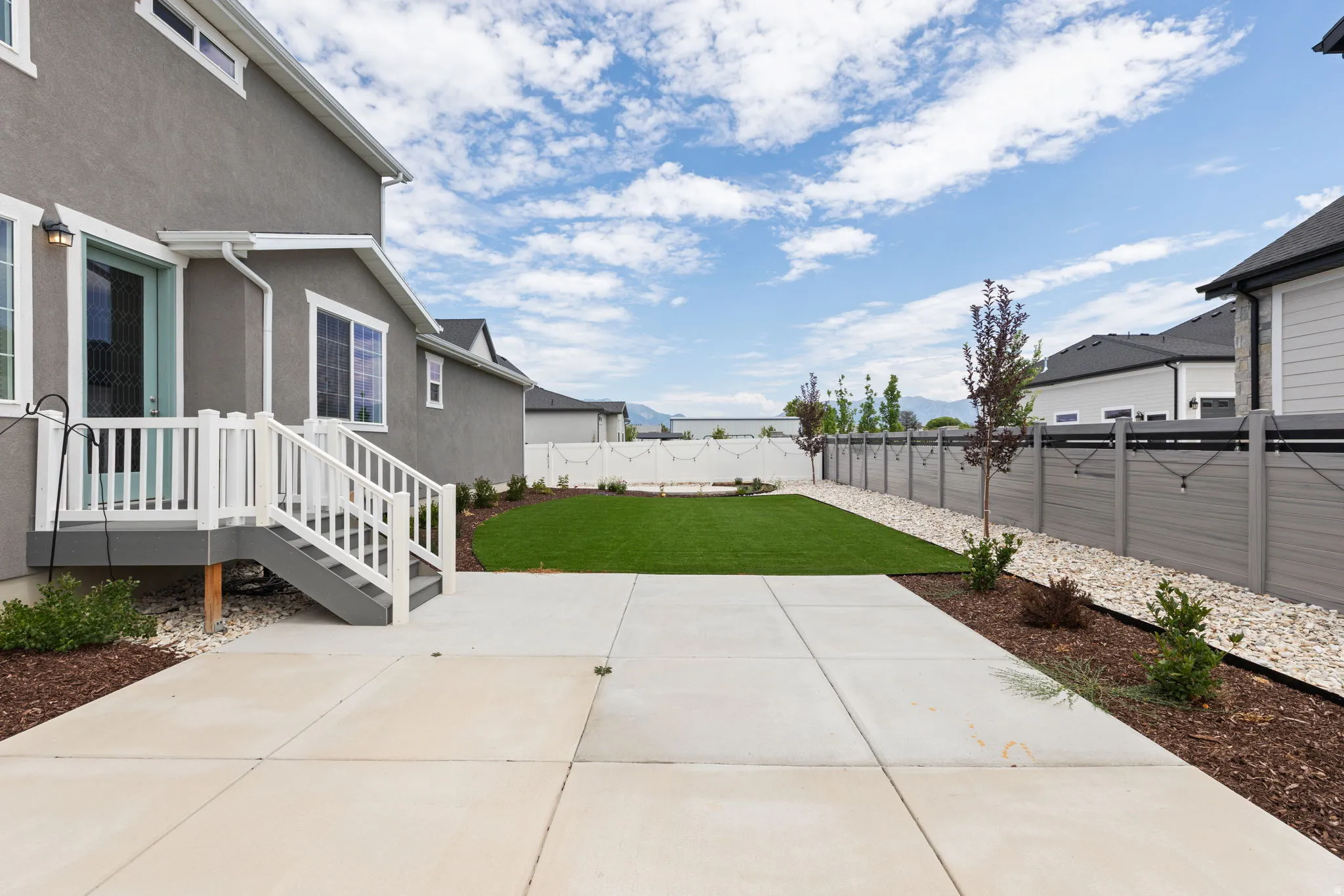 Expansive concrete patio with direct access to a manicured artificial turf lawn