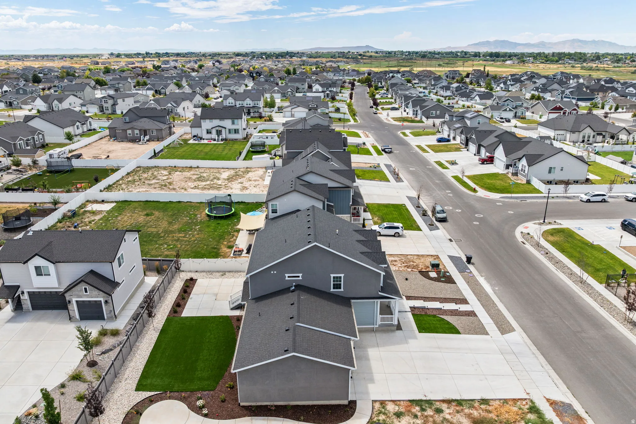 Expansive residential development featuring a variety of single-family homes with dark roofing, light-colored exteriors, and attached garages