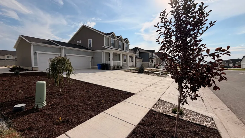 Welcoming front exterior featuring a two-story colonial-style home with multiple gables, attached two-car garage with panel doors, and a concrete driveway