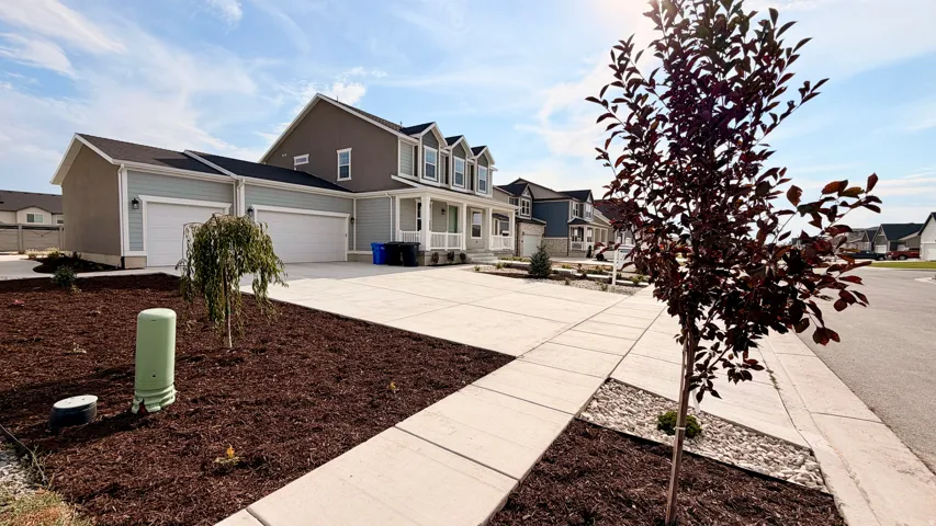 Two-story home with a two-car garage, concrete driveway, and front porch with columns