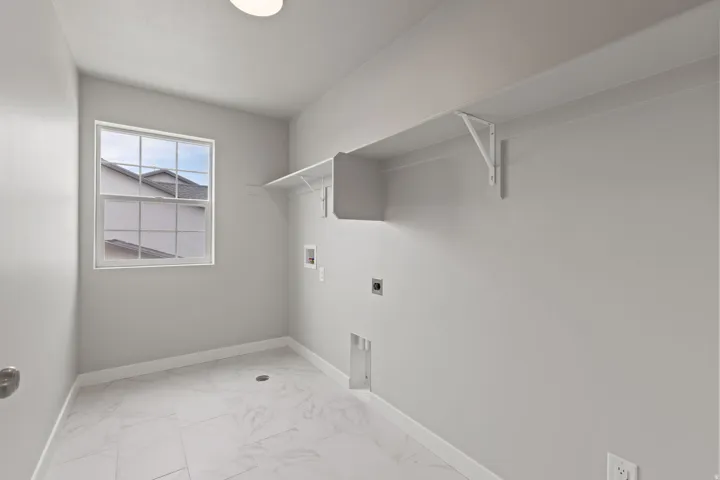 Utility room featuring a window, overhead shelving, and white tile flooring