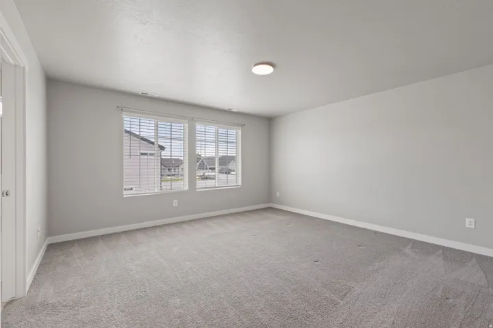 Spacious room featuring gray carpet flooring, light gray wall paint, and white trim