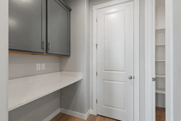 Built-in desk with a white countertop and gray cabinetry