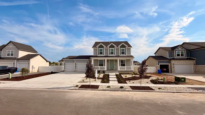 Two-story residence featuring a gray exterior with white trim, front porch, multiple dormer windows, and a three-car garage