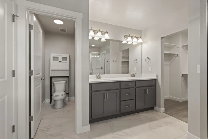 Bathroom featuring a dual vanity with grey cabinetry, white countertops, and brushed nickel fixtures