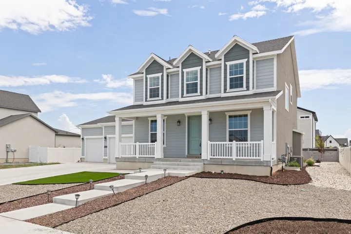 Two-story residence featuring light gray siding, white trim, and a covered front porch with white railings