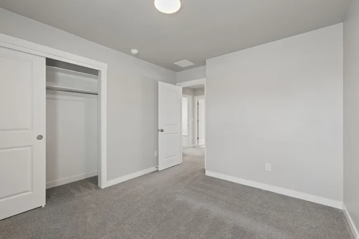 Bedroom featuring light gray walls, gray carpet, white trim, and a double-sliding closet with integrated shelving and hanging rod