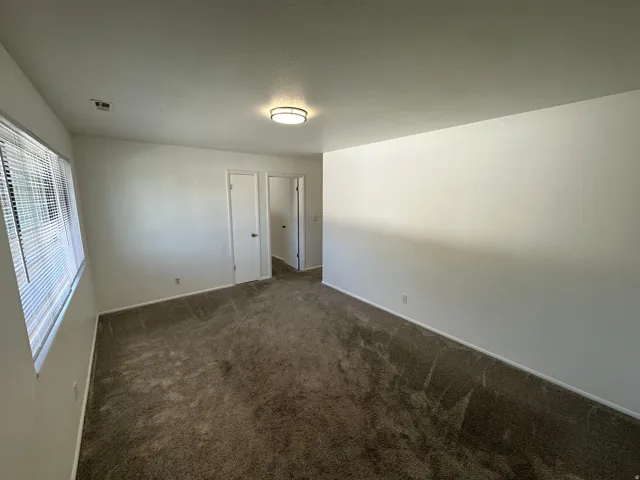 Bright interior room with brown patterned carpeting, white walls, and white baseboards