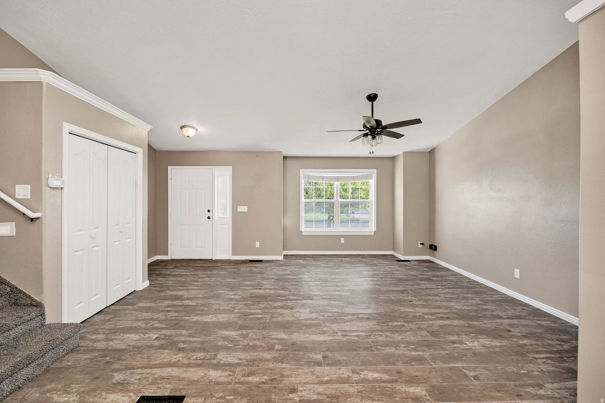 Spacious entry and living area featuring wood-finish flooring, a contemporary ceiling fan, and a double front door with sidelight