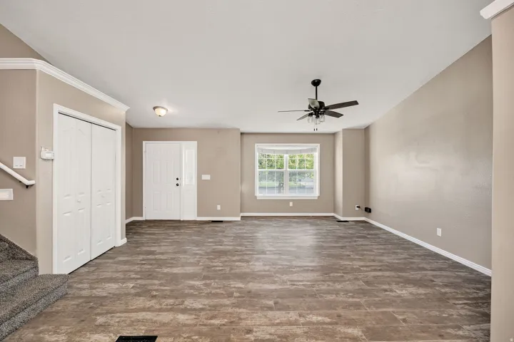 Spacious entry and living area featuring wood-finish flooring, a contemporary ceiling fan, and a double front door with sidelight