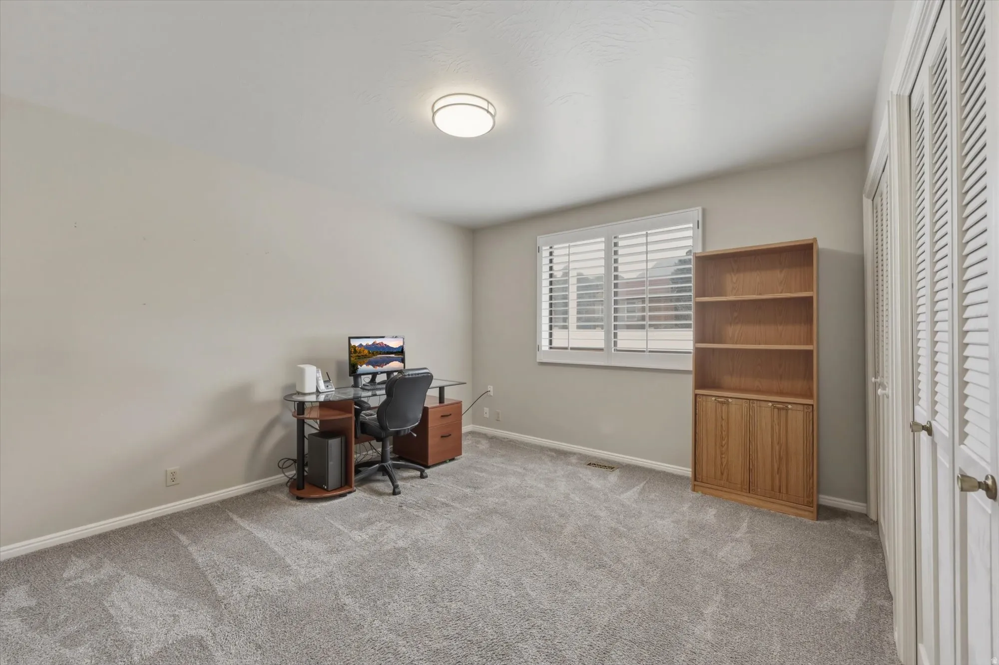Room featuring neutral-toned carpeting, a window with horizontal blinds, and a flush-mount ceiling light