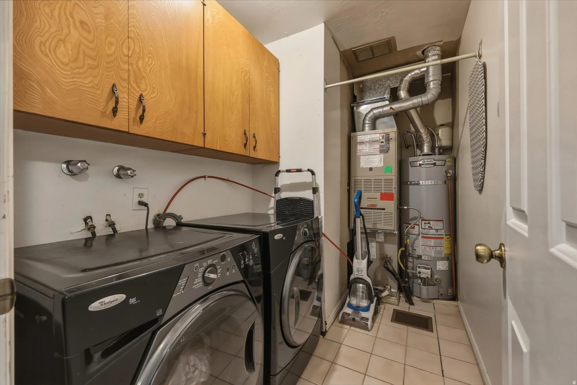 Dedicated utility area featuring overhead wood-finish cabinetry