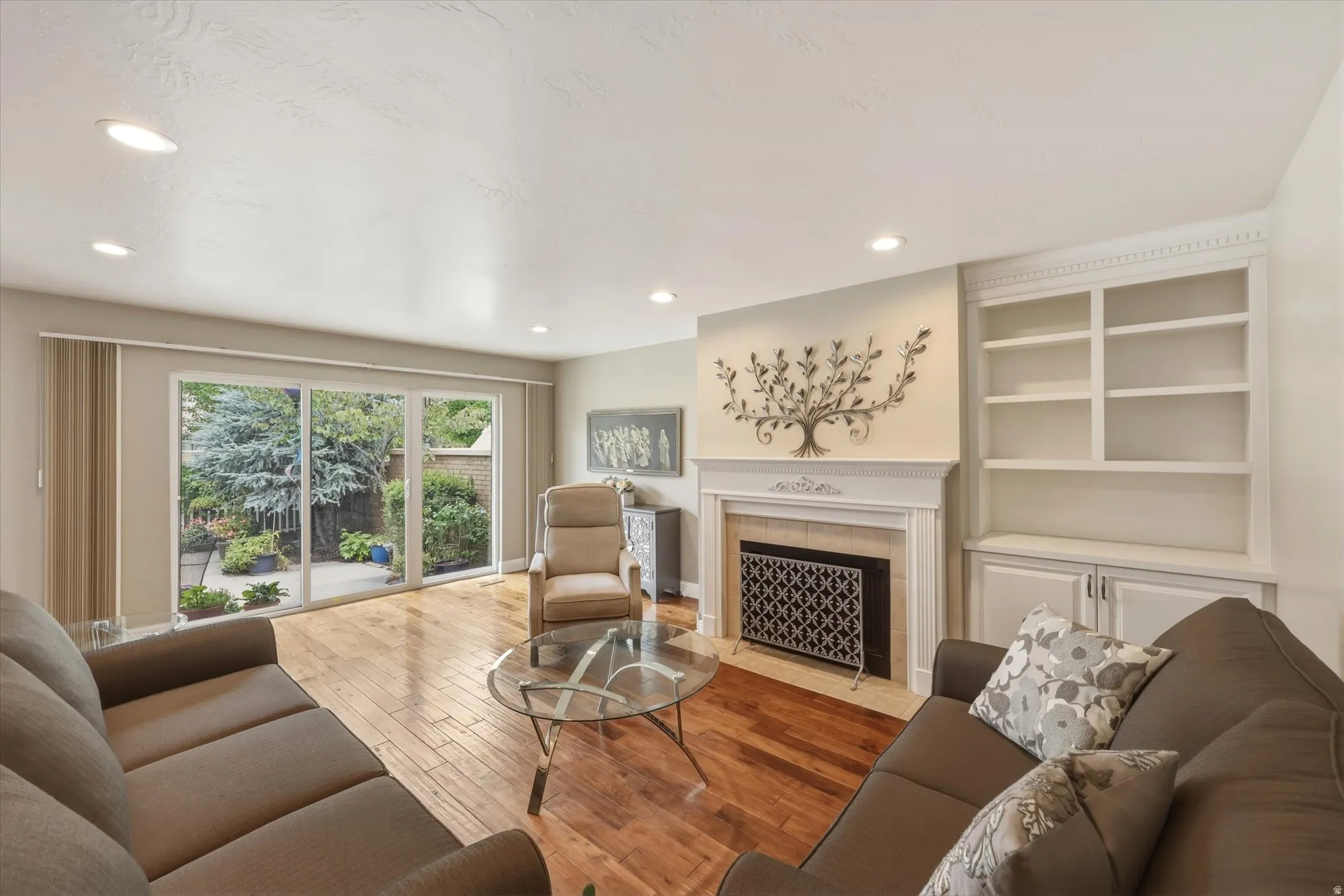 Living area featuring wood-finish flooring, a fireplace with a decorative mantel, and built-in shelving