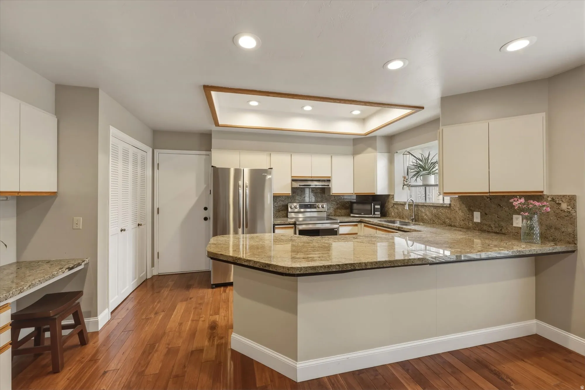 Kitchen featuring wood-finish flooring, granite countertops, and stainless steel appliances