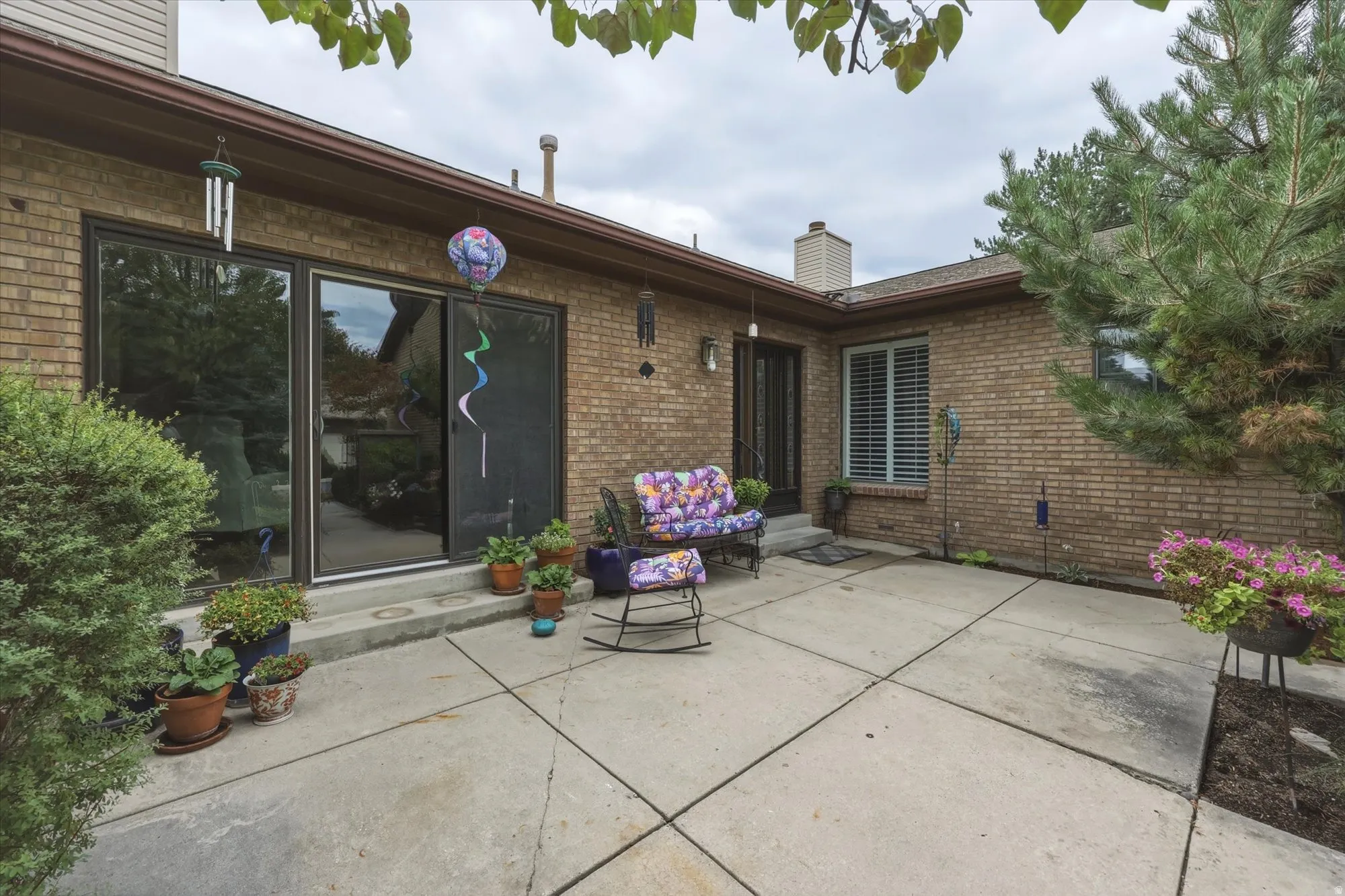 Brick exterior featuring a concrete patio with perimeter landscaping