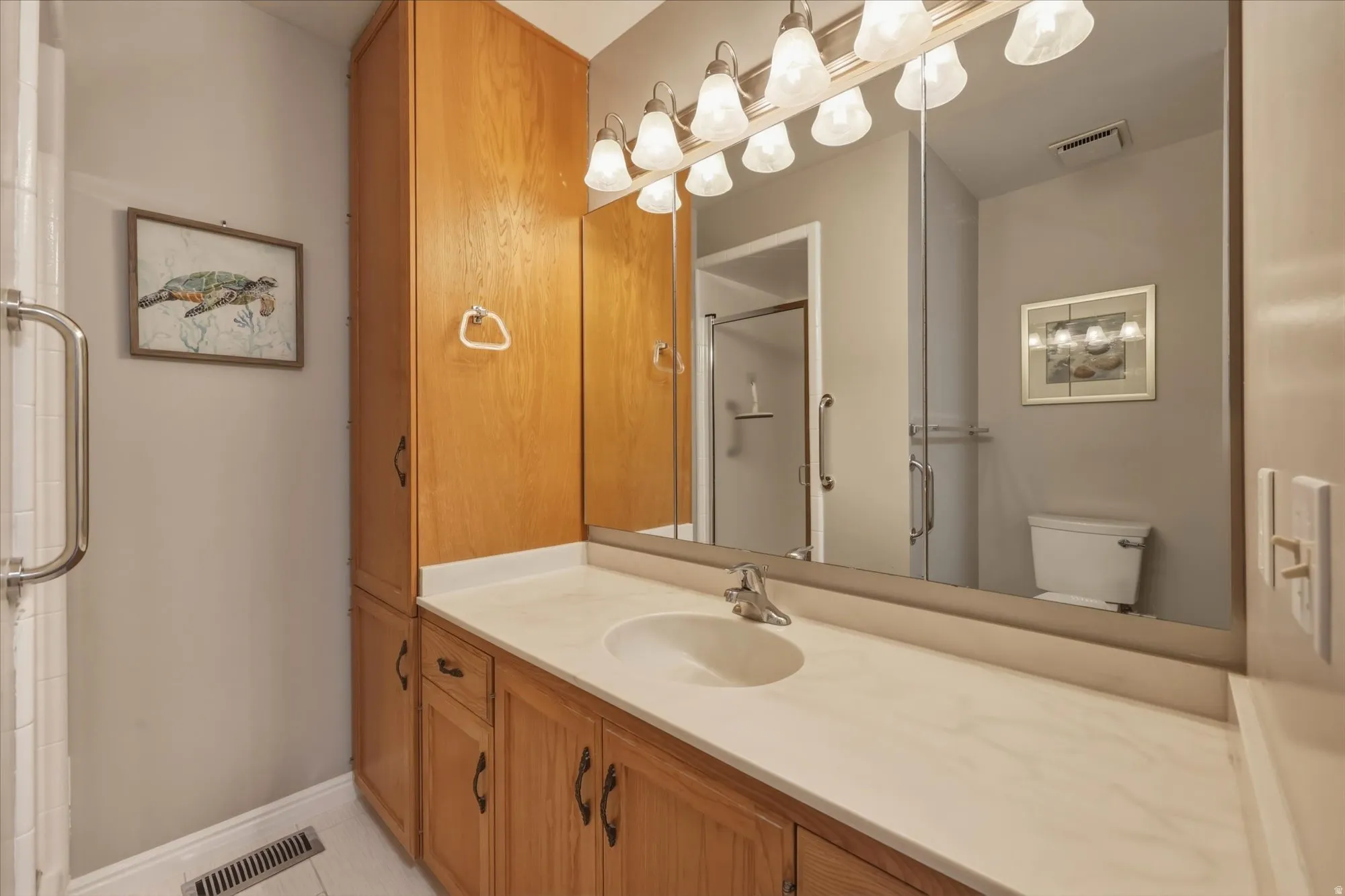 Bathroom vanity featuring wood-finish cabinetry, a single basin sink, and a light-colored countertop