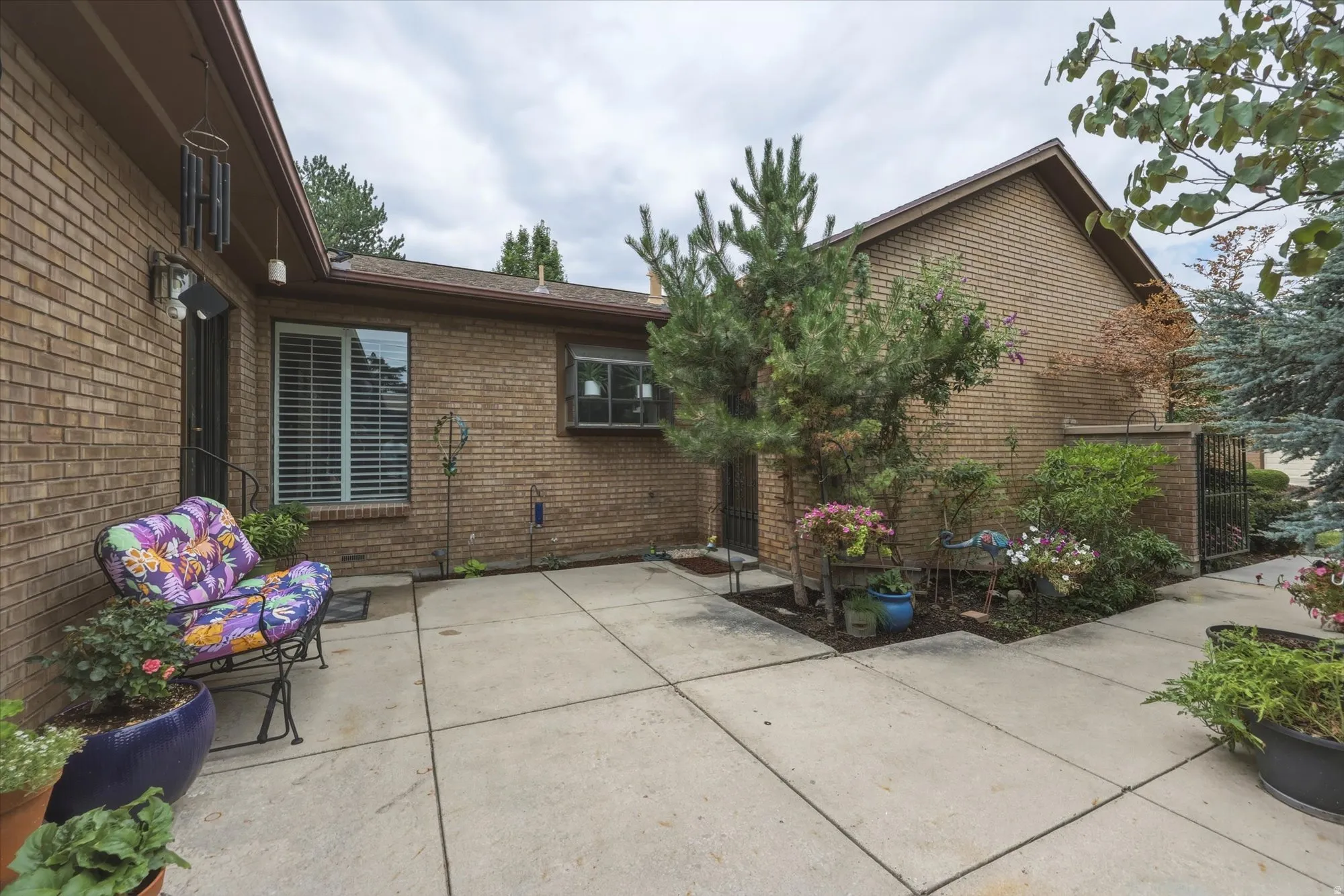Expansive concrete patio area with brick exterior and mature landscaping