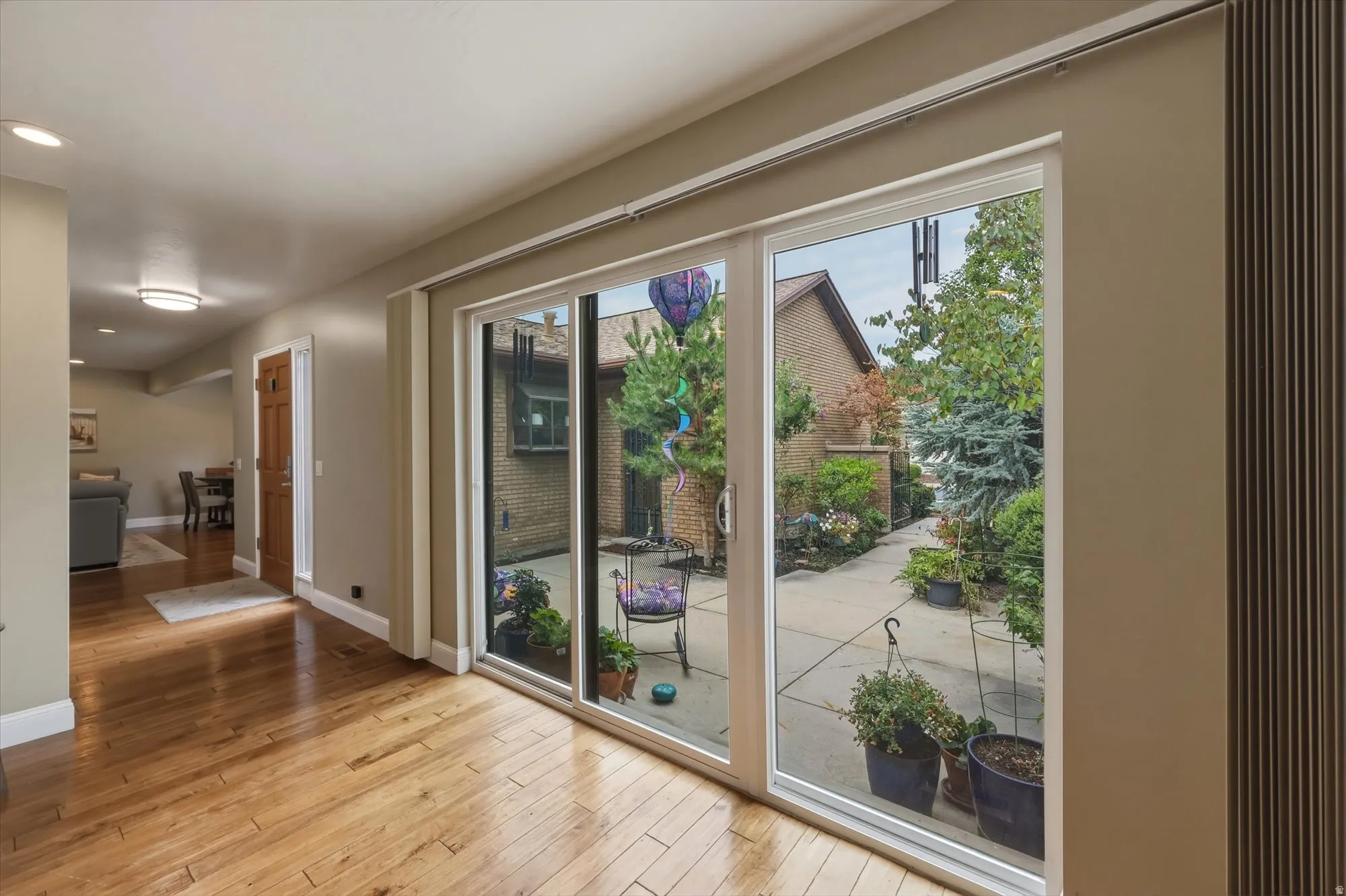 Sliding glass doors opening to a concrete patio with mature plantings