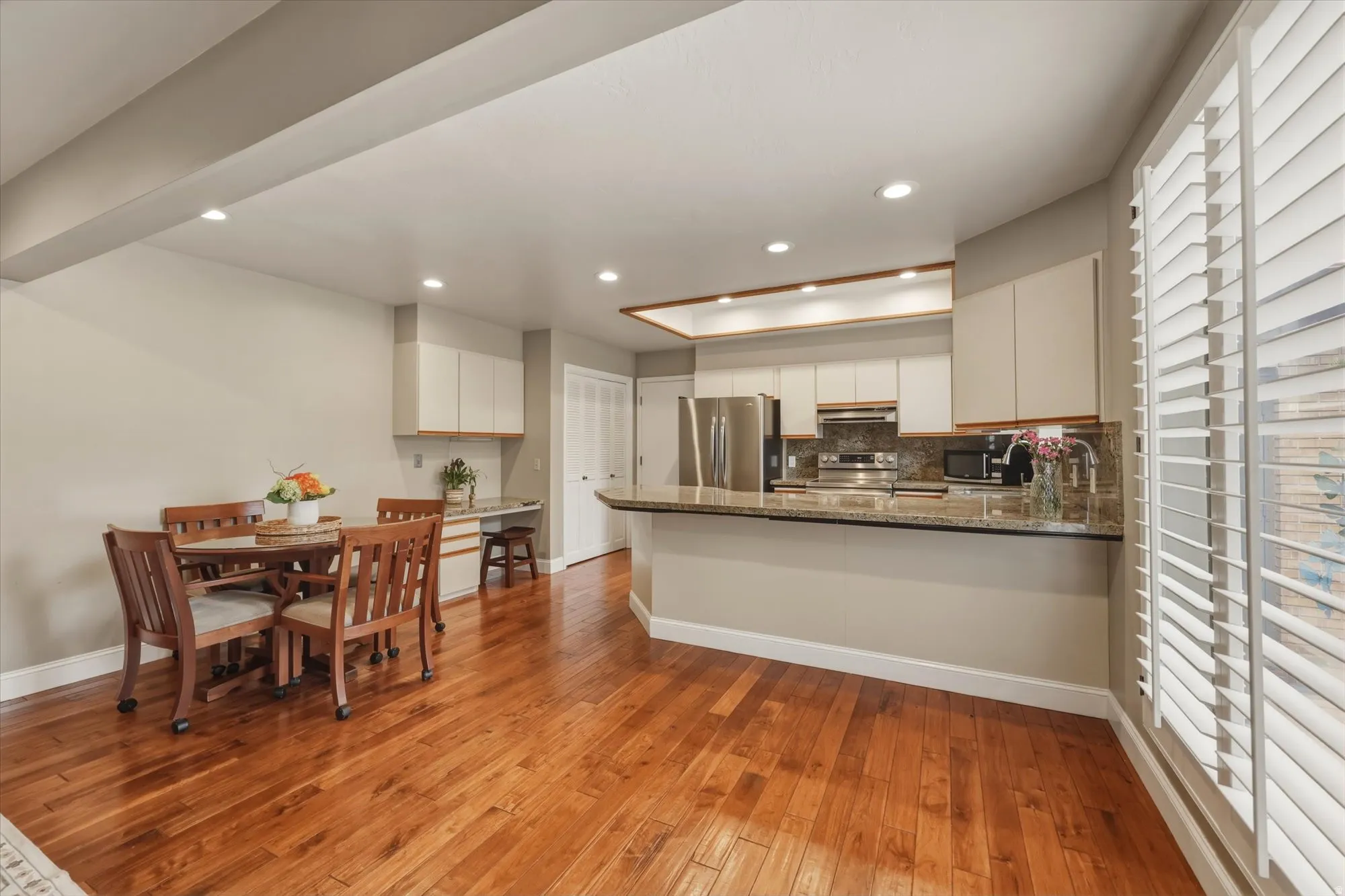 Open-concept living space featuring wood-finish flooring, recessed lighting, and plantation shutters
