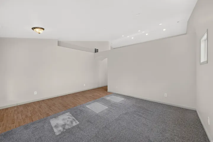Vaulted ceilings with recessed lighting, wood-finish flooring, and gray carpeting