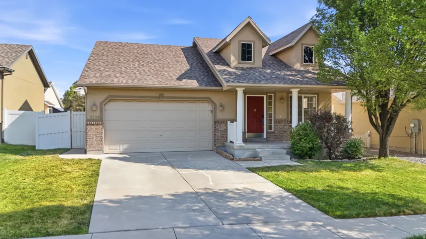 Stucco exterior with brick accents, attached two-car garage, covered porch, dormer windows, and a concrete driveway