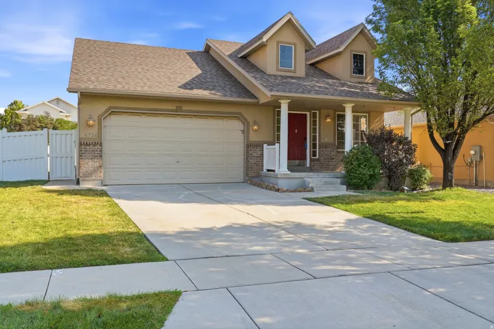 Stucco exterior with brick accents, prominent two-car garage, covered porch with white columns, dormer windows, and a red entry door