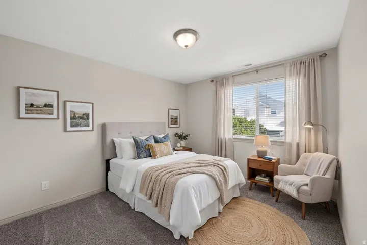 Plush carpet flooring, light-colored walls, a ceiling-mounted light fixture, and a large window with blinds