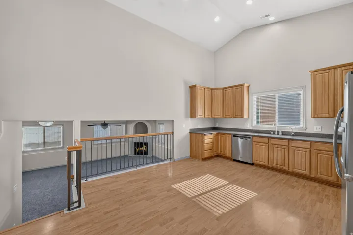 Vaulted ceilings, wood-finish flooring, natural wood cabinetry, stainless steel appliances, and a built-in fireplace