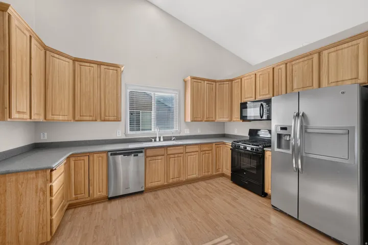Kitchen featuring wood-finish cabinetry, stainless steel appliances, gray countertops, and wood-finish flooring