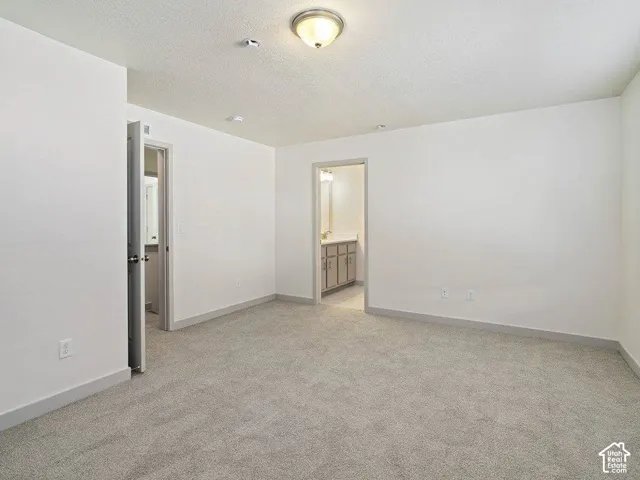 Spacious room featuring light gray carpeting and white walls