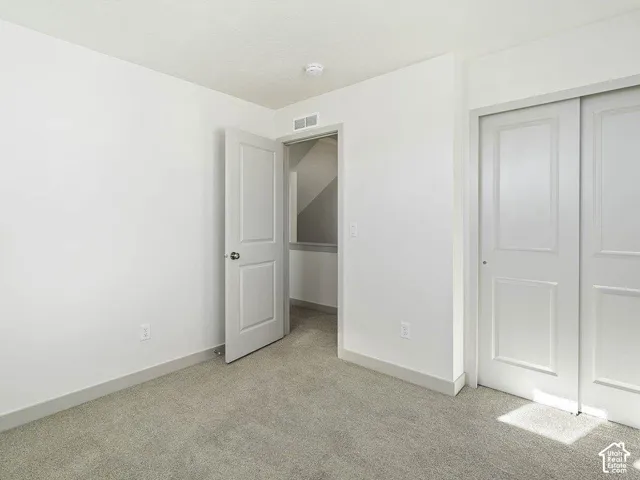 Bedroom featuring neutral carpeting, white walls, white trim, and a white sliding closet door