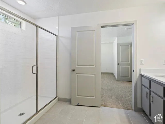 Bathroom featuring a glass-enclosed shower with subway tile, a translucent transom window, and a gray vanity with a light-colored countertop