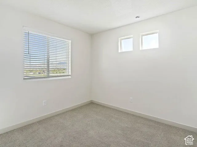 Room featuring a large window with horizontal blinds, two high-set square windows, light gray carpeting, and white painted walls