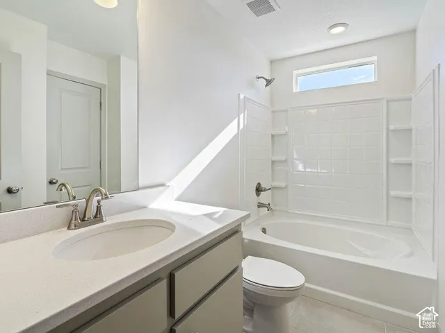 Bathroom featuring a white bathtub with tile surround, a single vanity with a light-colored countertop, and a rectangular mirror