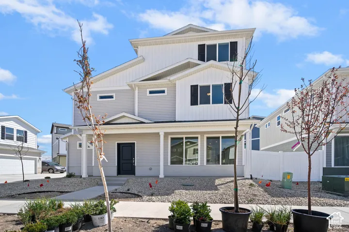 Contemporary exterior with multi-level design, light gray siding, dark window shutters, an inviting front porch, and a dark entry door