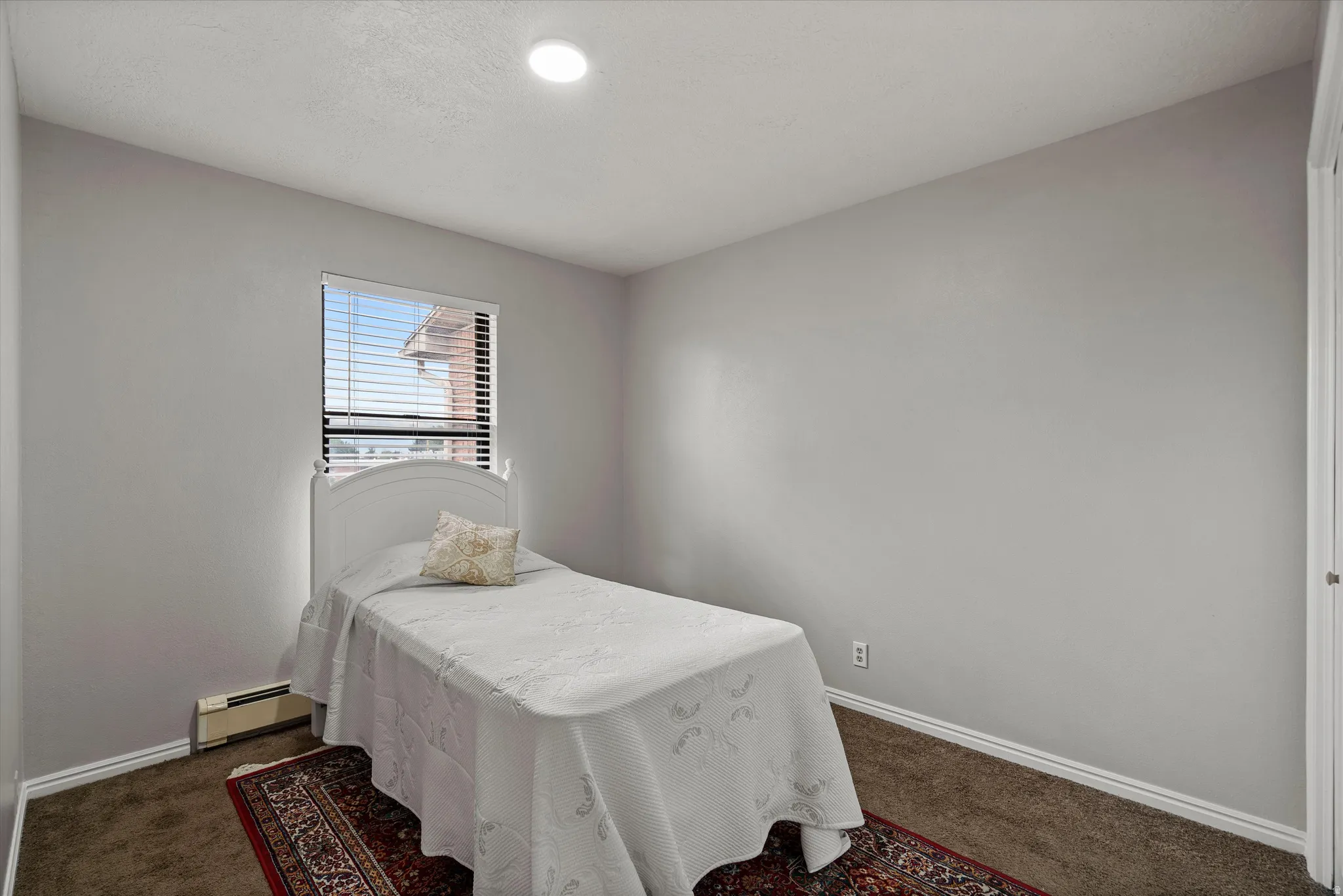Bedroom featuring light gray walls, brown carpet, white baseboards, and a single window with white blinds