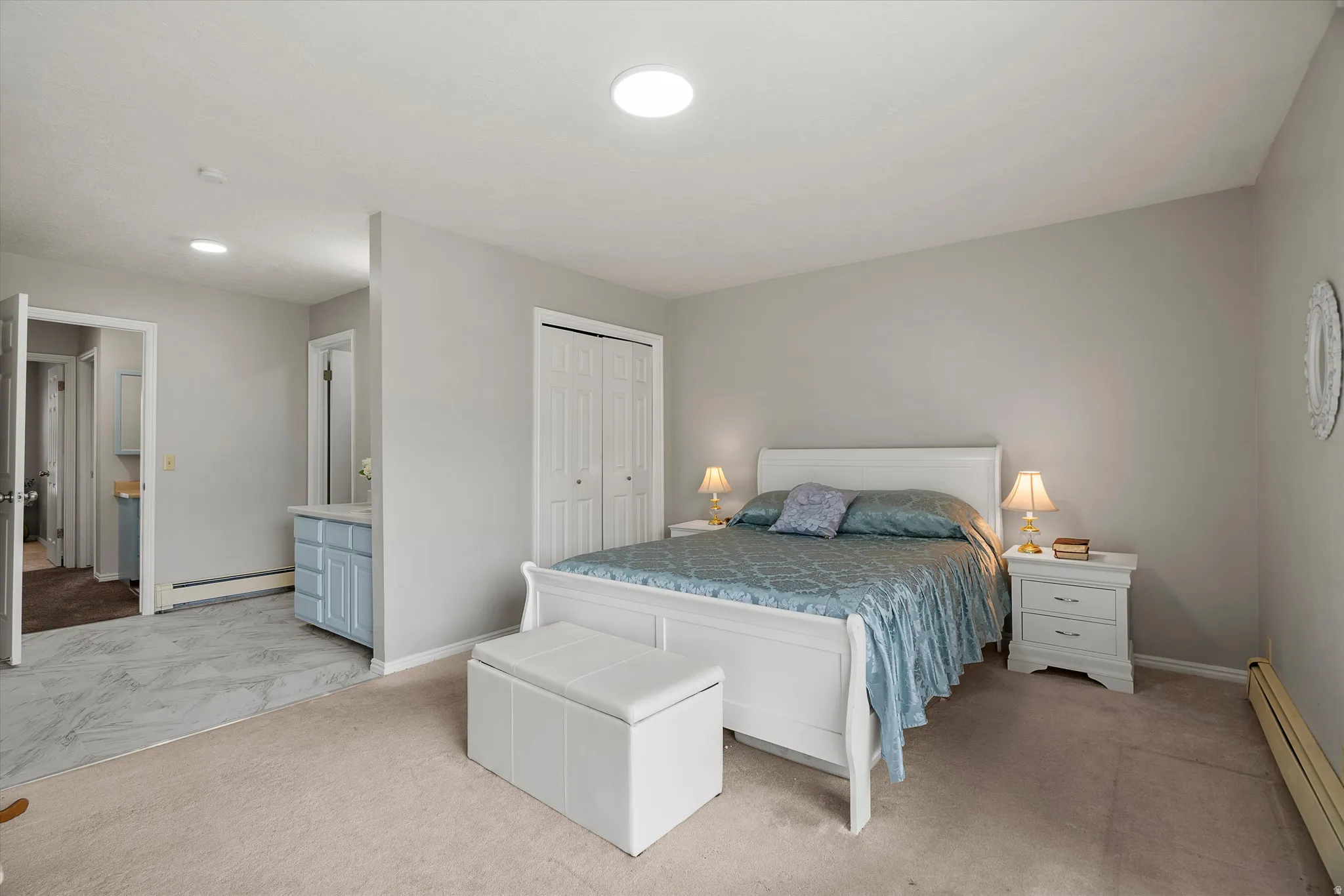 Bedroom featuring light gray wall paint, a white bed frame, and soft carpet flooring