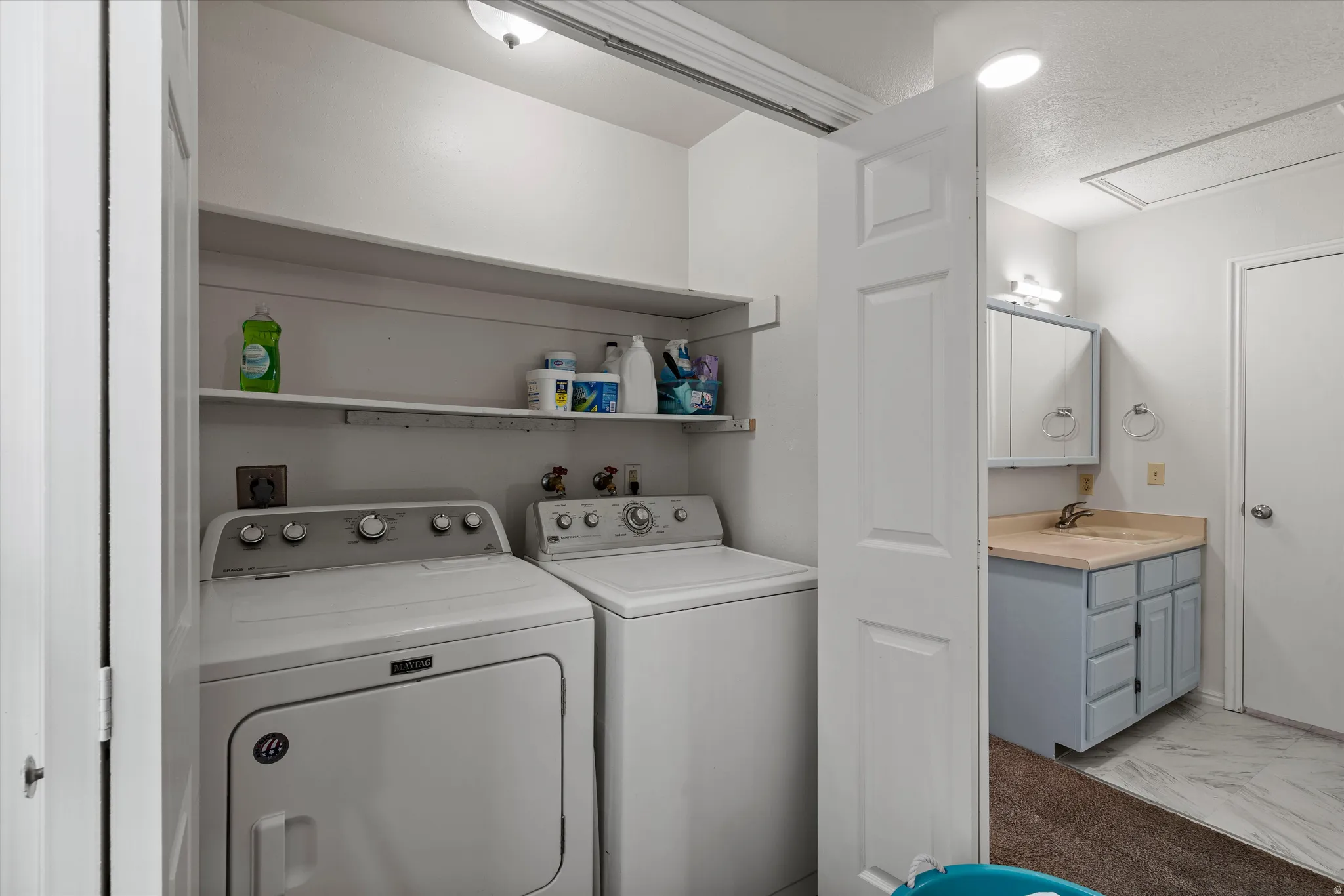 Dedicated laundry area featuring a washer and dryer, accompanied by a shelving unit for storage