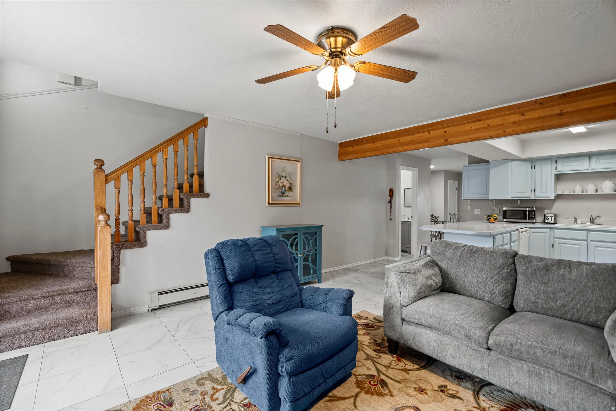 Living area featuring light gray walls, white tile flooring, and a ceiling fan with light fixture
