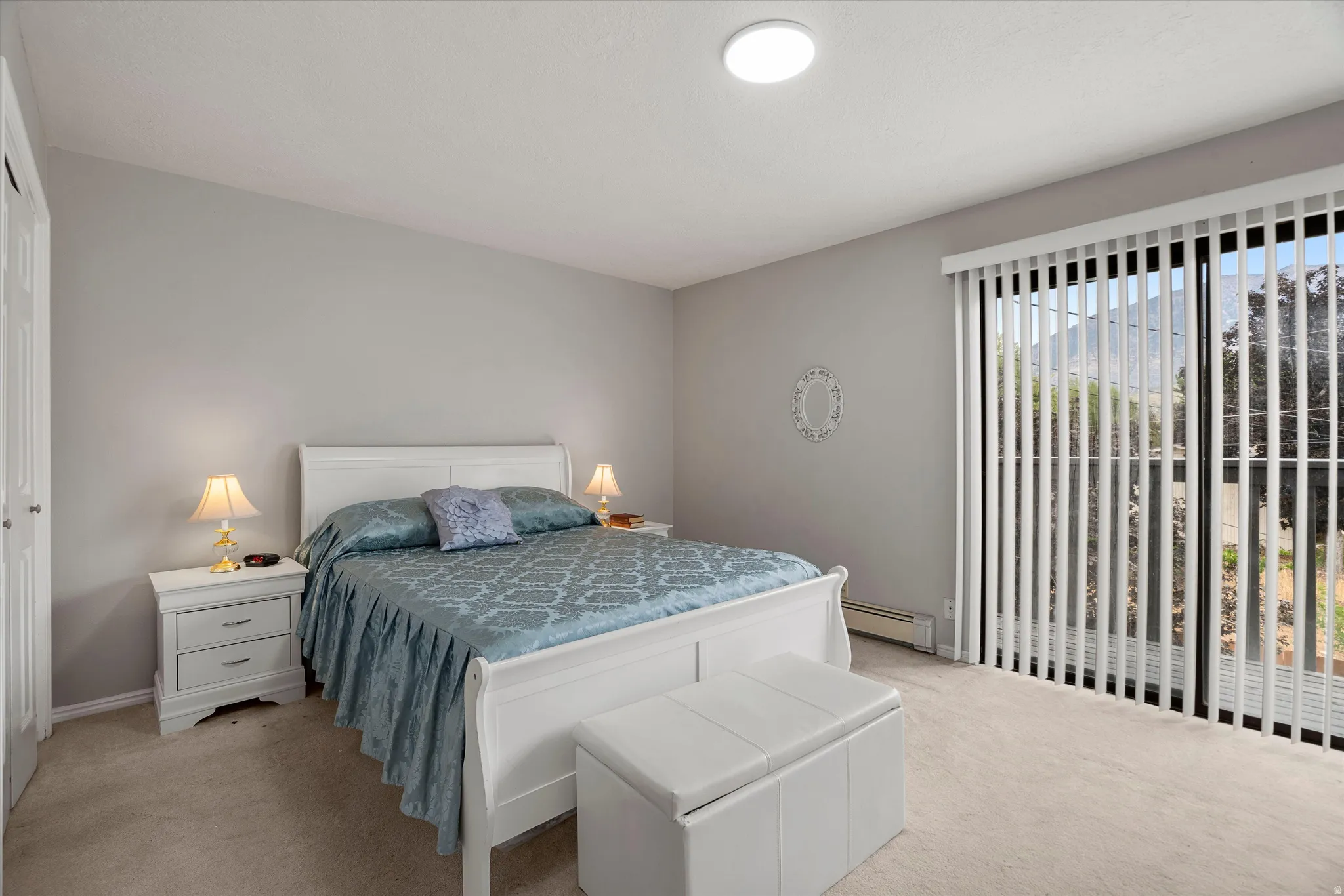 Primary bedroom with balcony. Carpeted room featuring a ceiling-mounted light fixture, light gray wall paint, and a white bi-fold closet door