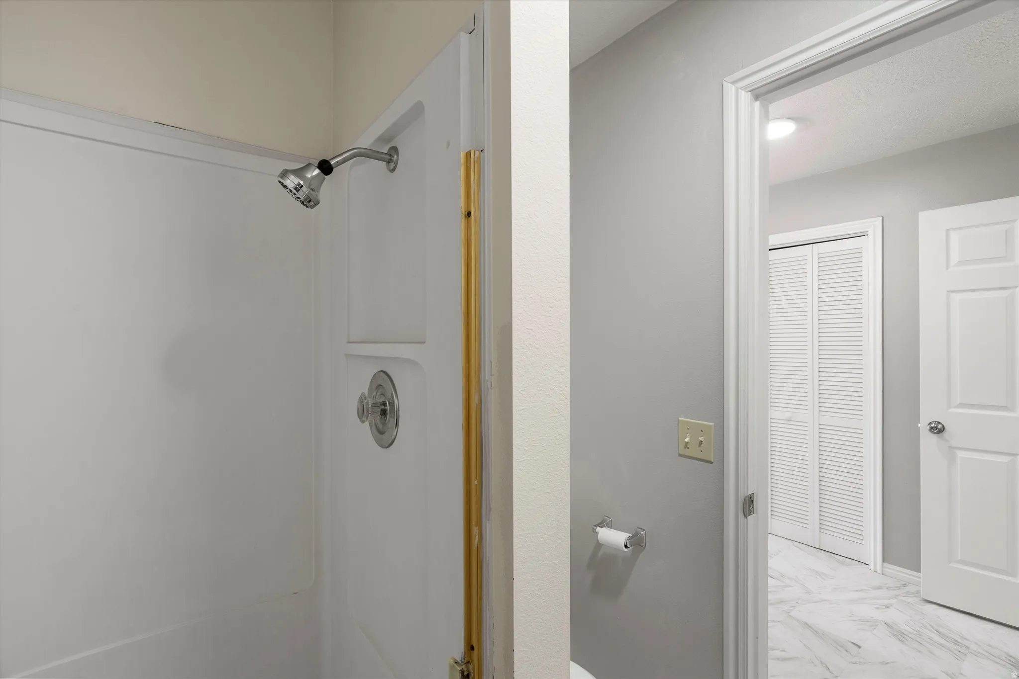 Primary bathroom. White shower enclosure with integrated shelving and chrome fixtures