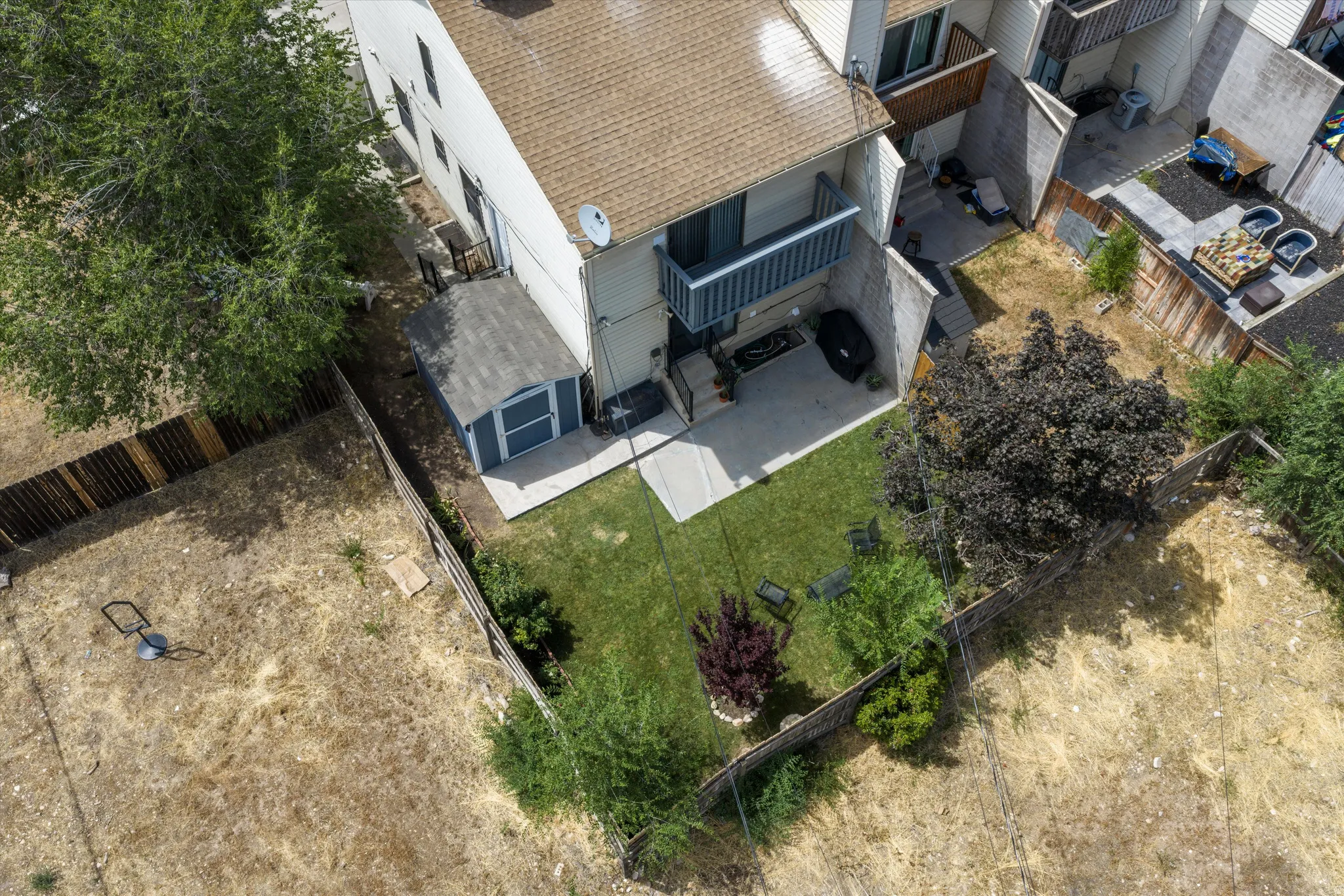 Private fenced backyard with a manicured lawn, concrete patio, and mature landscaping