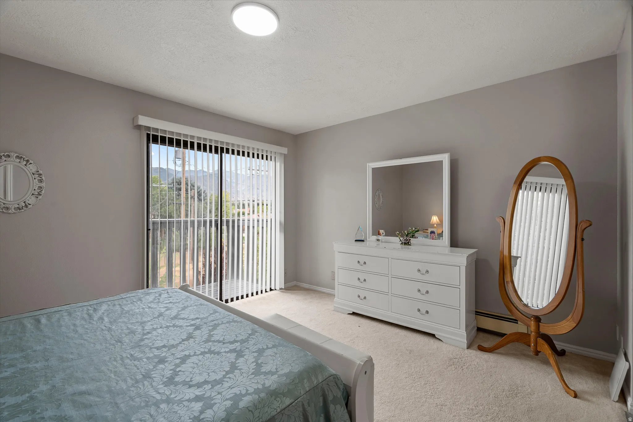 Sliding glass door with vertical blinds offering exterior access and mountain scenery