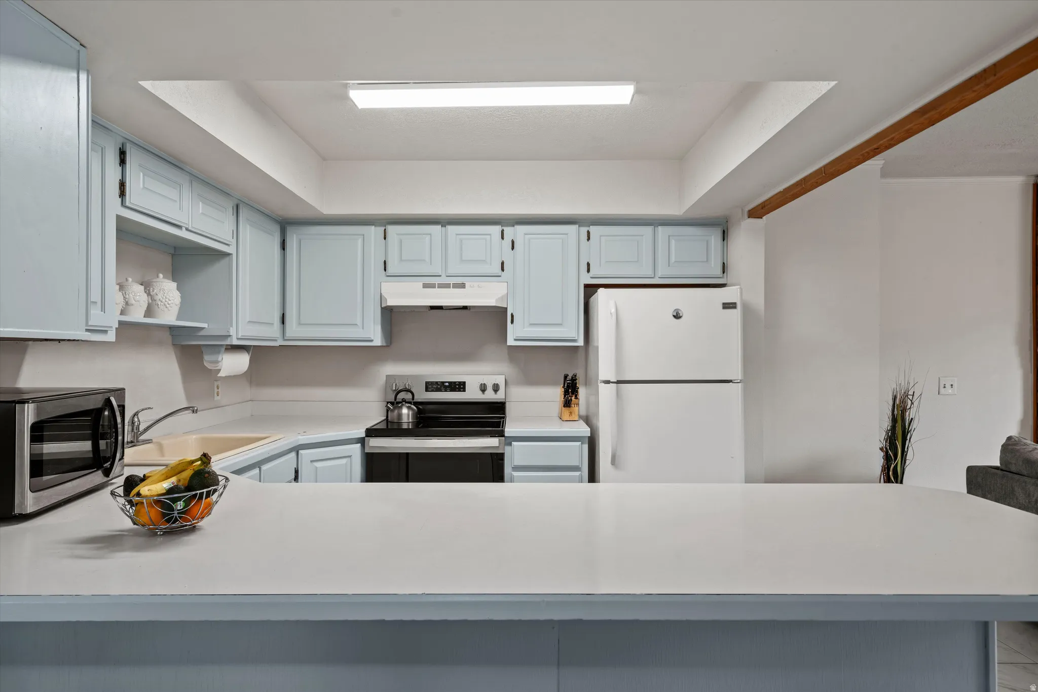 Kitchen featuring light blue cabinetry, white countertops, and a white appliance package including a refrigerator and range