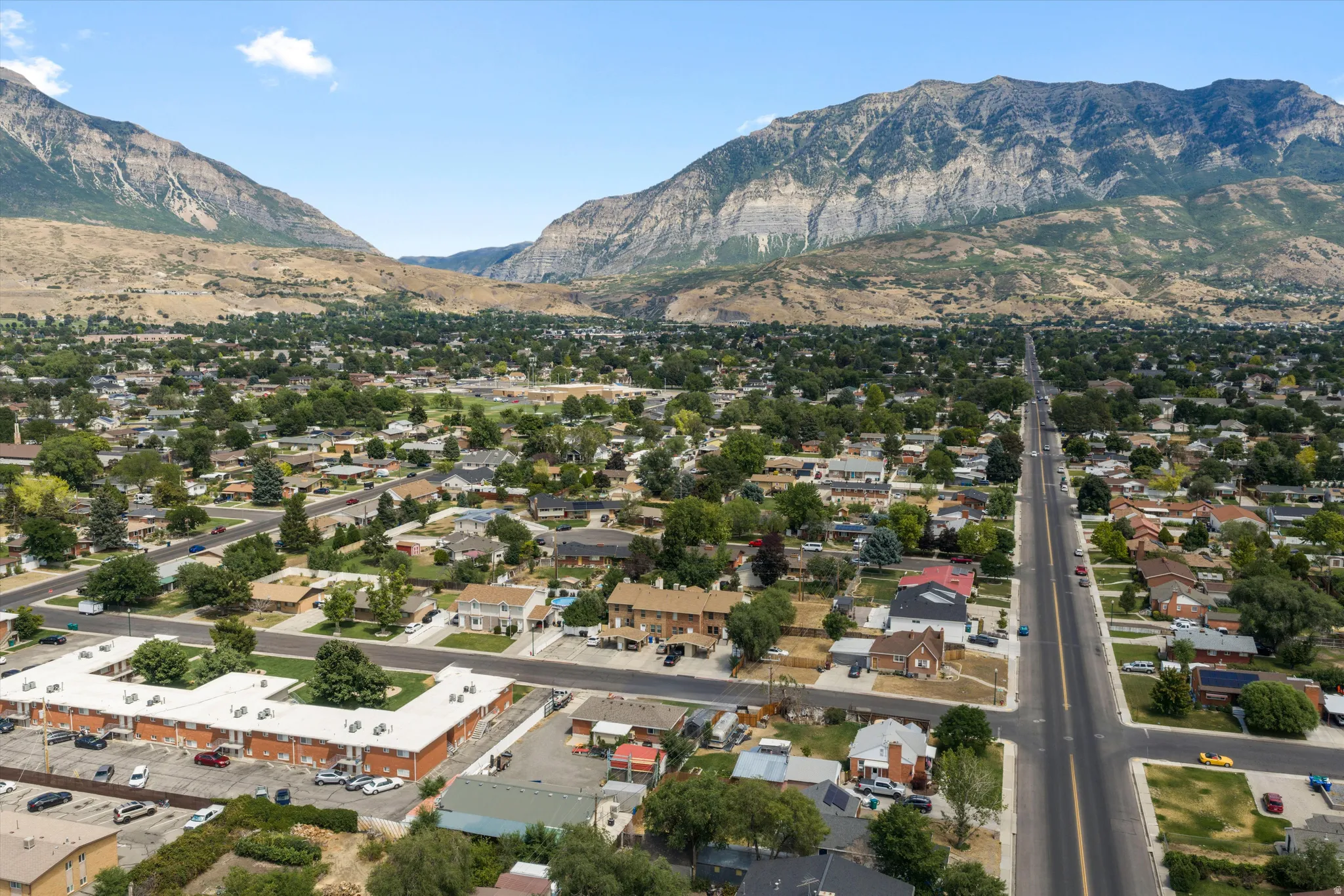 Expansive aerial perspective showcasing a residential neighborhood with mature trees and a prominent mountain backdrop
