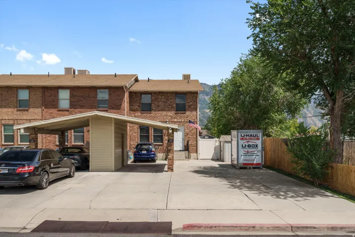 Brick exterior multi-unit property featuring a carport and ample paved parking