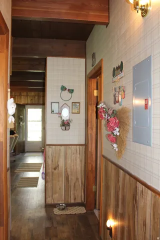 Interior hallway featuring wood-finish flooring, wood paneling, and exposed wood beam ceilings