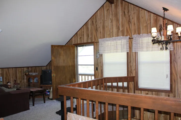 Upper-level living area featuring wood-paneled walls and a sloped white ceiling
