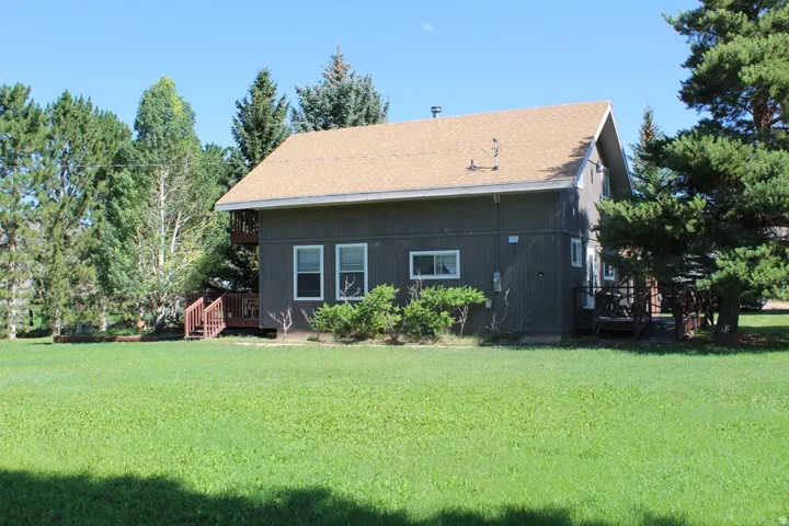 Two-story property featuring dark gray vertical siding, a light brown shingle roof, and multiple exterior decks